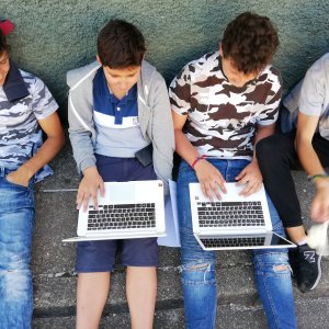alunos sentados com computador portátil no colo